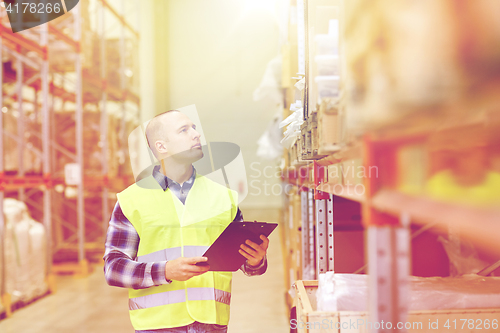 Image of man with clipboard in safety vest at warehouse