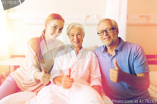 Image of happy family visiting senior woman at hospital