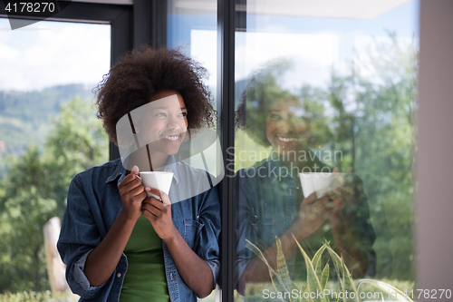 Image of African American woman drinking coffee looking out the window