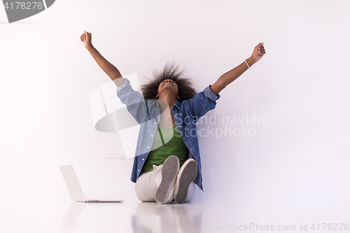 Image of african american woman sitting on floor with laptop