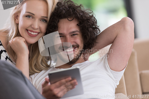 Image of couple relaxing at  home with tablet computers