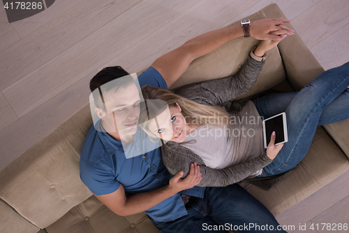 Image of youg couple in living room with tablet top view