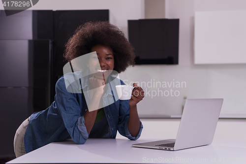 Image of smiling black woman in modern kitchen