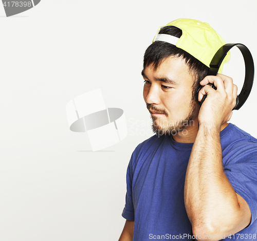 Image of young asian man in hat and headphones listening music on white b