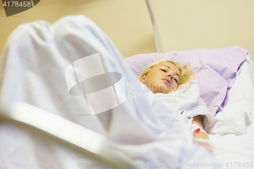 Image of Bedridden female patient recovering after surgery in hospital care.