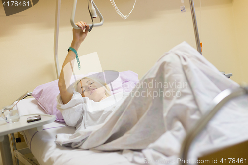 Image of Bedridden female patient recovering after surgery in hospital care.