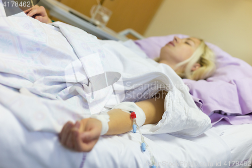 Image of Bedridden female patient recovering after surgery in hospital care.