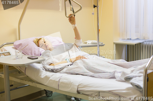 Image of Bedridden female patient recovering after surgery in hospital care.