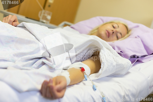 Image of Bedridden female patient recovering after surgery in hospital care.