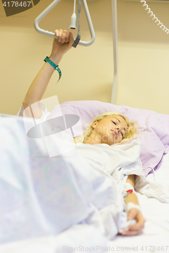 Image of Bedridden female patient recovering after surgery in hospital care.