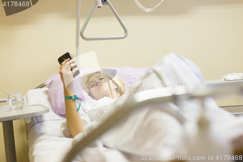 Image of Bedridden female patient recovering after surgery in hospital care.