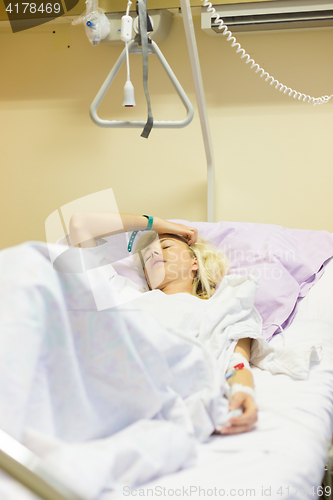 Image of Bedridden female patient recovering after surgery in hospital care.