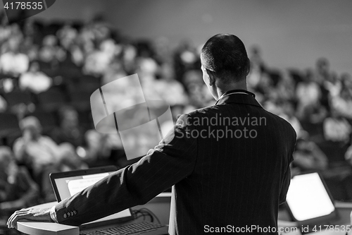 Image of Public speaker giving talk at business event.