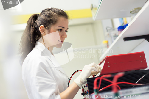 Image of Life science researcher setting voltege on power supply to run electrophoresis.