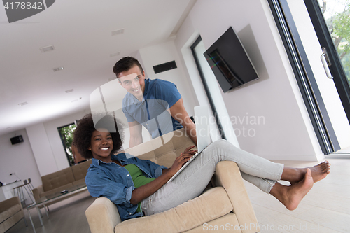 Image of multiethnic couple on an armchair with a laptop