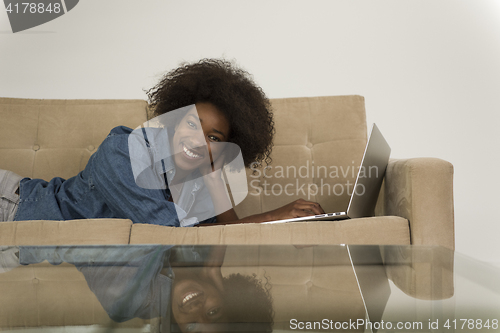 Image of African American woman using laptop on sofa