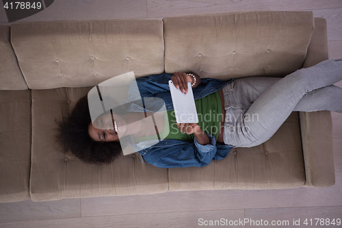 Image of african american woman at home with digital tablet top view