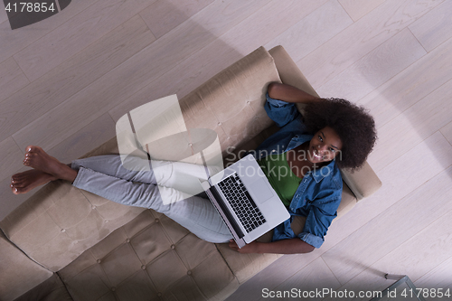 Image of African American woman using laptop on sofa top view