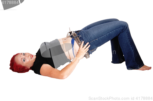 Image of Woman lying on floor pulling jeans up.