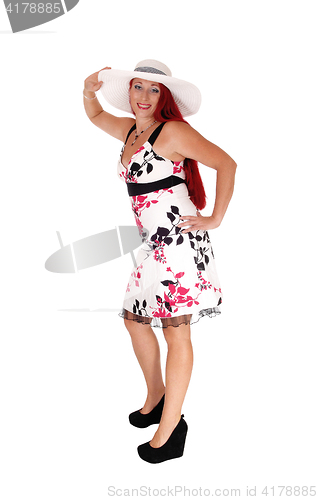 Image of Red haired woman standing with hat.