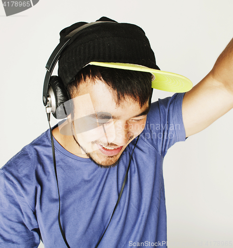 Image of young asian man in hat and headphones listening music on white b