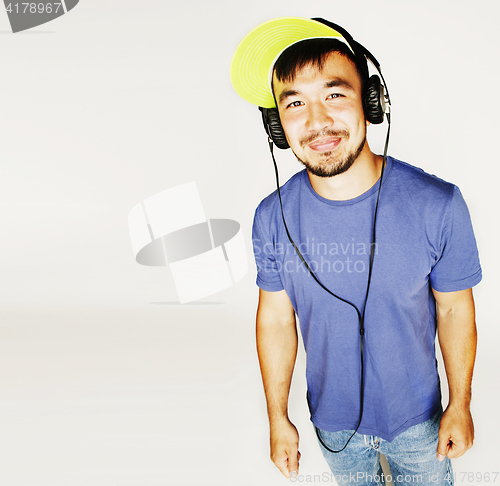 Image of young asian man in hat and headphones listening music on white b