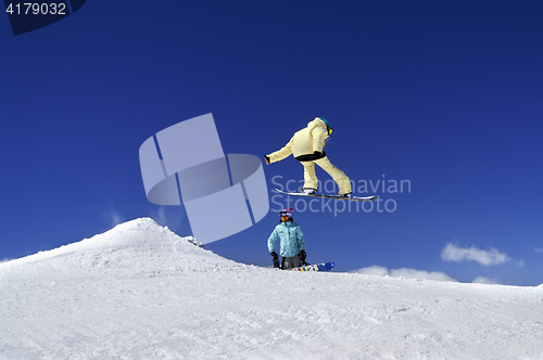 Image of Two snowboarders in terrain park at ski resort on sun winter day