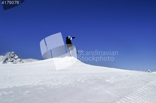 Image of Snowboarder jump in terrain park at ski resort on sun winter day