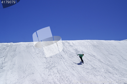 Image of Snowboarder downhill in terrain park and blue clear sky at ski r