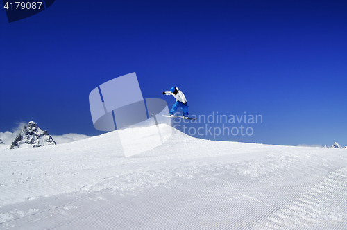 Image of Snowboarder jump in snow park at ski resort on sunny winter day