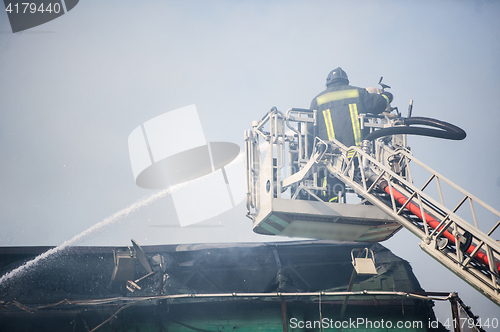 Image of Firefighters in action fighting, extinguishing fire, in smoke.