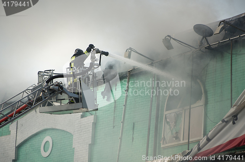 Image of Firefighters in action fighting, extinguishing fire, in smoke.