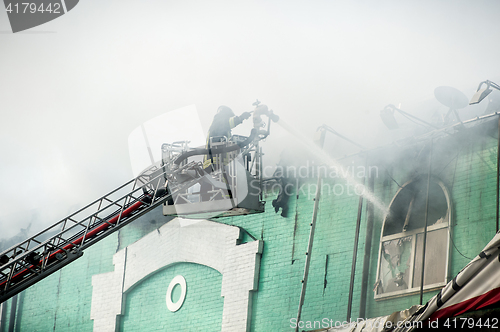 Image of Firefighters in action fighting, extinguishing fire, in smoke.