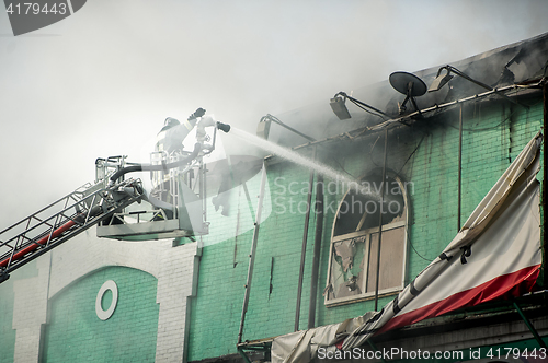 Image of Firefighters in action fighting, extinguishing fire, in smoke.