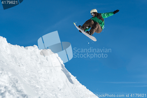 Image of Snowboarder jumping against blue sky