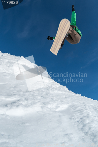 Image of Snowboarder jumping against blue sky