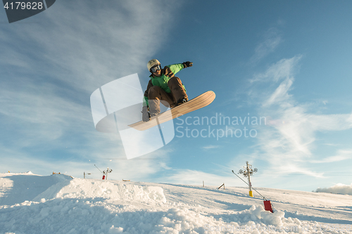 Image of Snowboarder jumping against blue sky