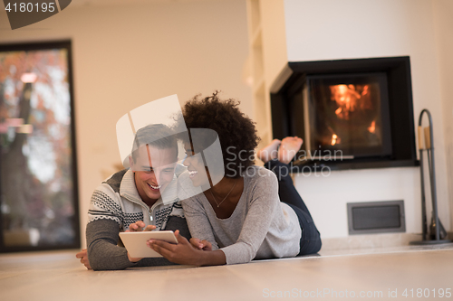 Image of multiethnic couple used tablet computer on the floor