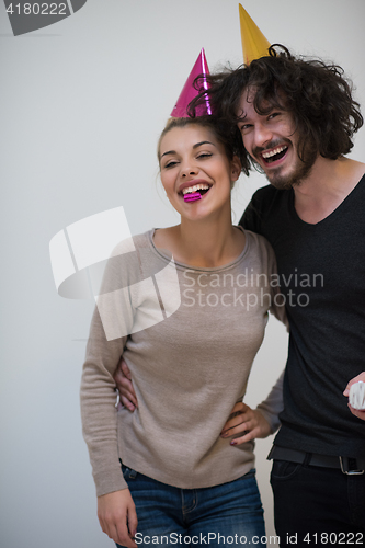 Image of couple in party hats blowing in whistle