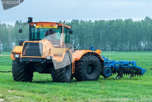 Image of Tractor operator plows the site in rain