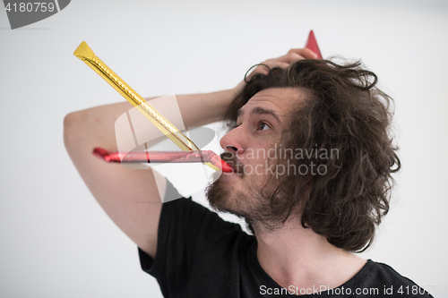 Image of Portrait of a man in party hat blowing in whistle