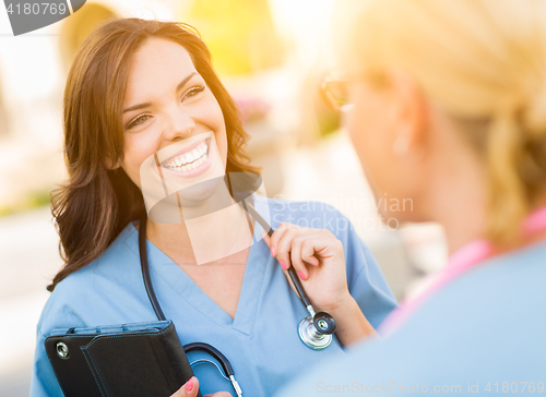 Image of Two Young Adult Professional Female Doctors or Nurses Talking Ou