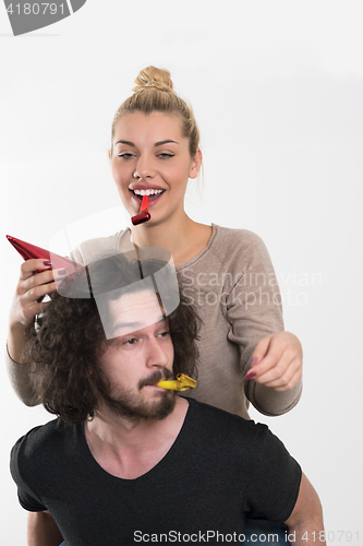 Image of couple in party hats blowing in whistle