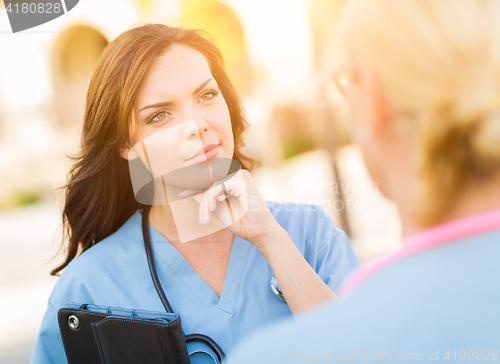 Image of Two Young Adult Professional Female Doctors or Nurses Talking Ou