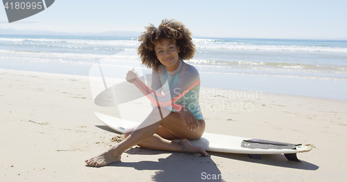 Image of Happy female sitting on a surfboard