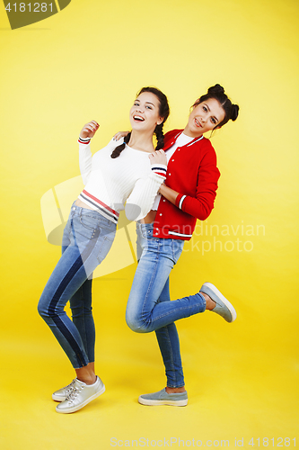 Image of lifestyle people concept: two pretty school girl having fun on yellow background, happy smiling students 