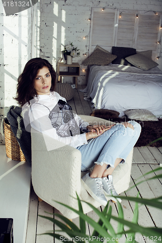 Image of young pretty woman in her bedroom sitting in chair, lifestyle people concept