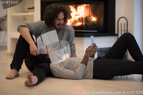 Image of multiethnic couple used tablet computer on the floor