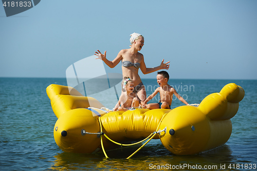 Image of two children with mom on the dinghy sailing at sea in summer