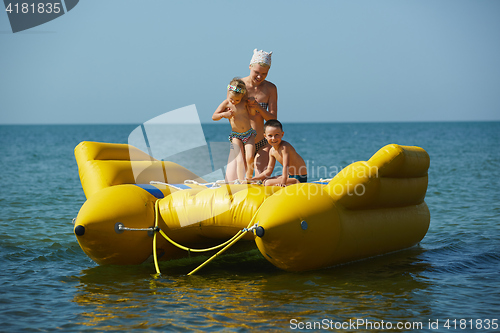 Image of two children with mom on the dinghy sailing at sea in summer